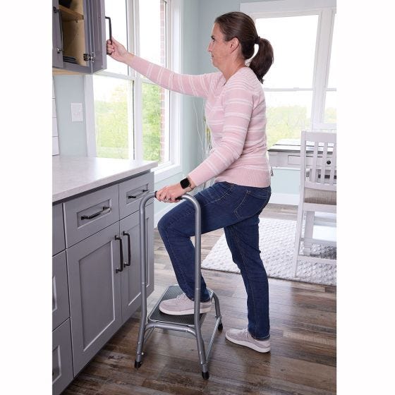 woman standing on stool to open cabinets woman standing on stool to open cabinets