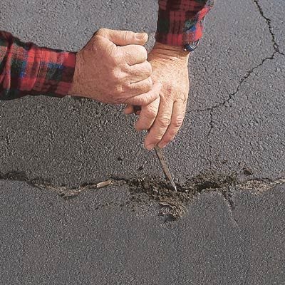 Model cleaning out crack in driveway